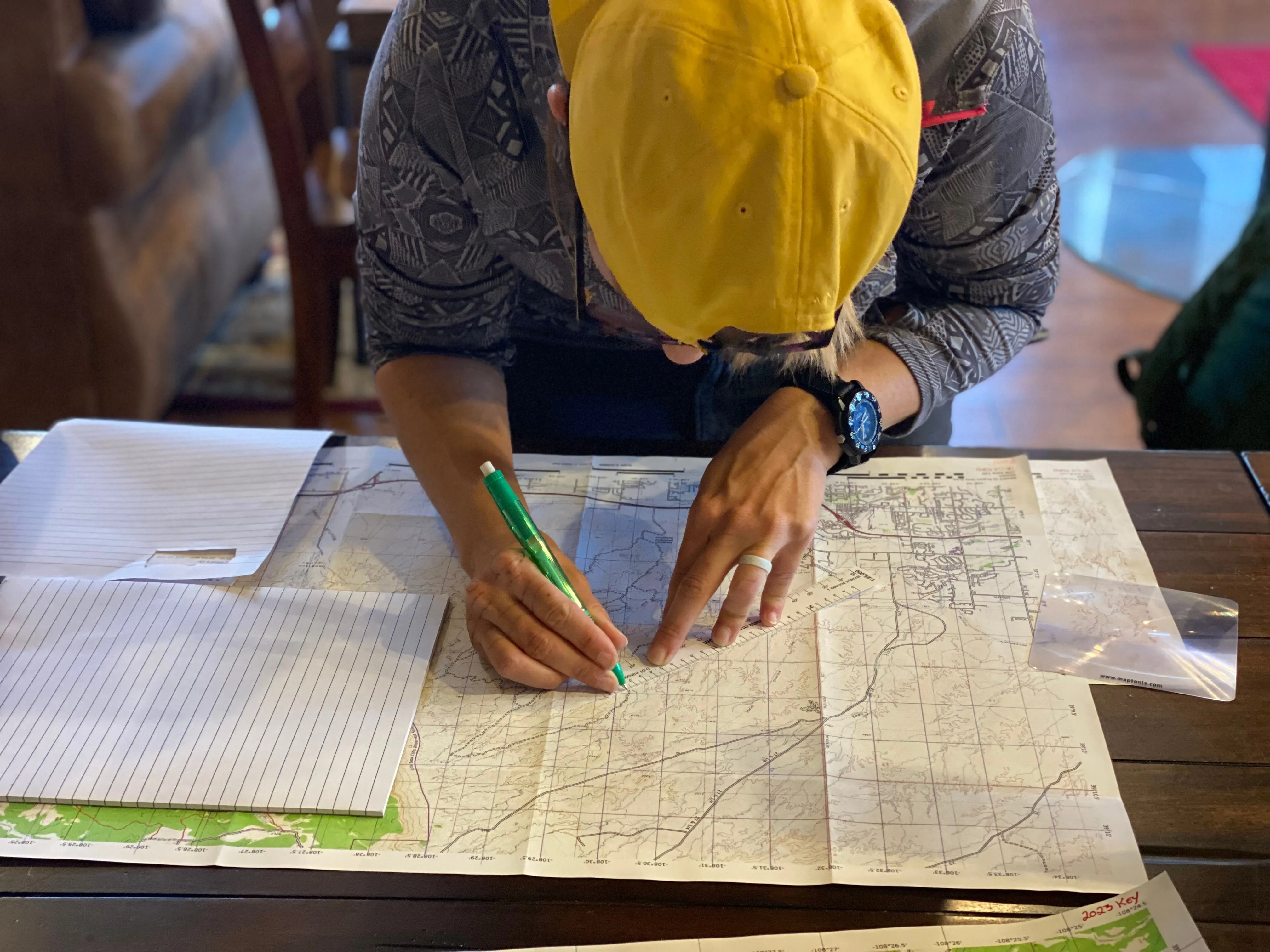 Individual mapping out a route indoors using a map and pen, possibly planning a journey.