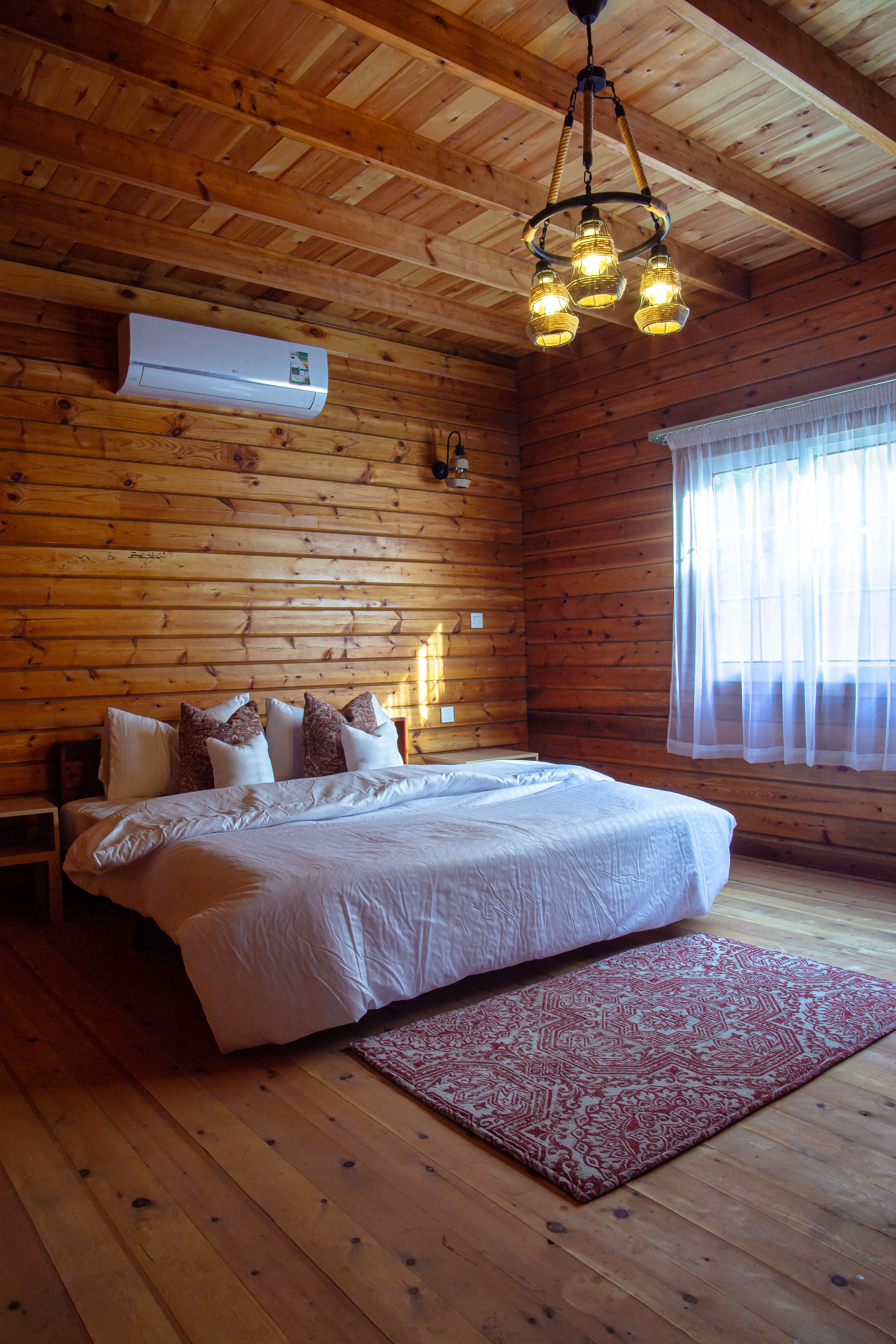 Inviting wooden bedroom with cozy bedding and natural light filtering through curtains.