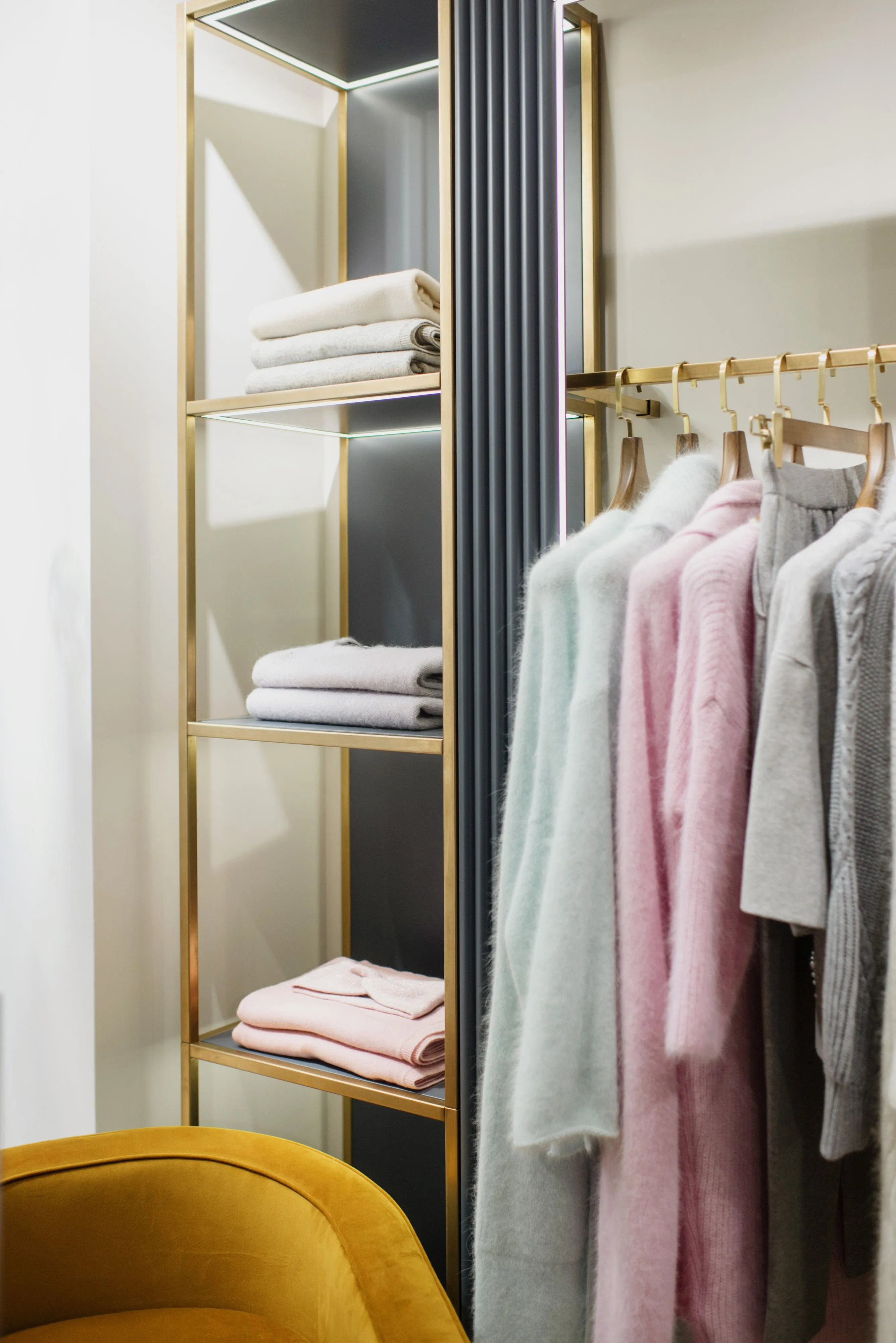 Stylish wardrobe featuring pastel clothing and neatly folded towels on elegant shelves.