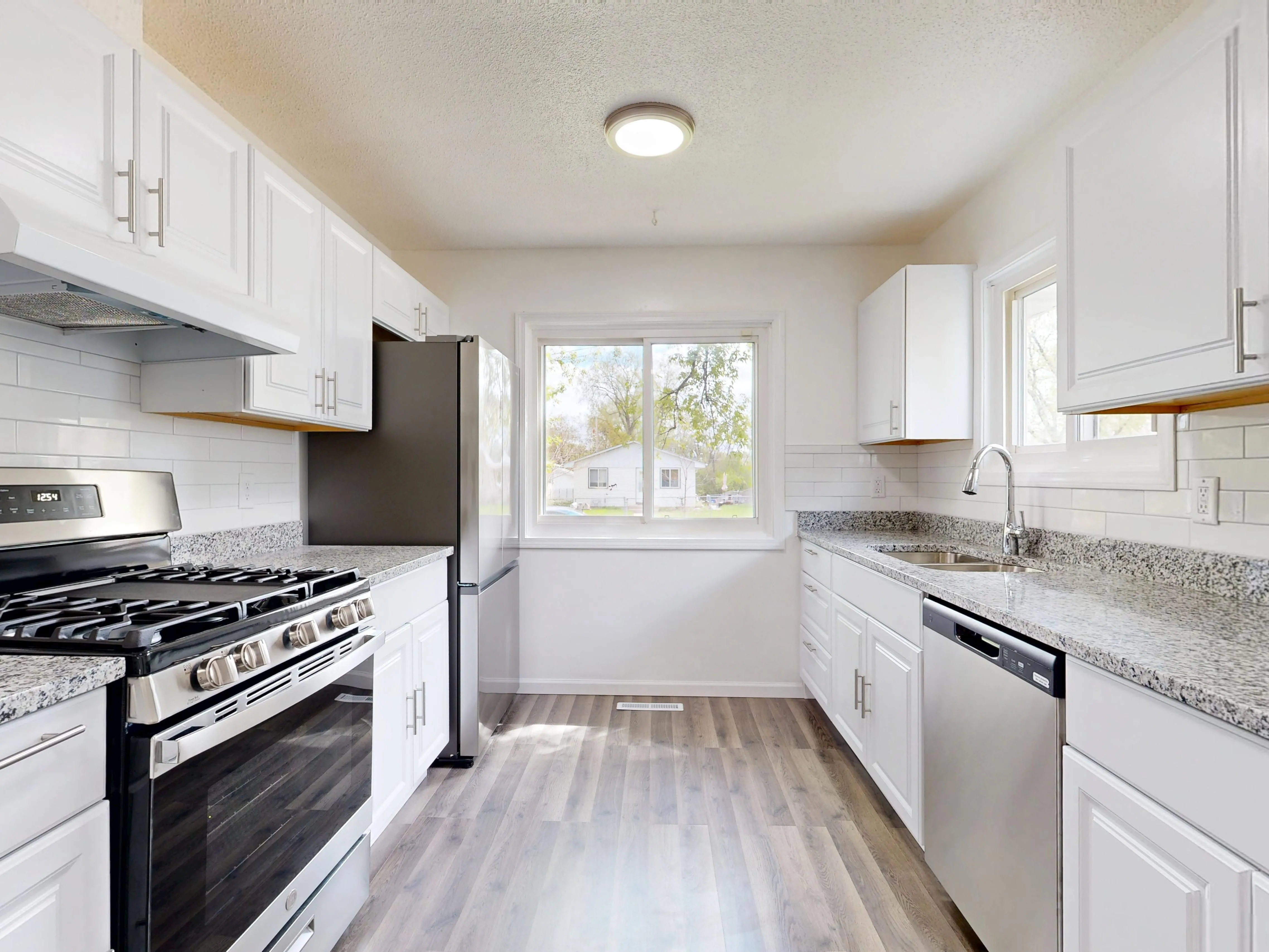 Bright, modern kitchen with white cabinets, granite countertops, and stainless steel appliances.