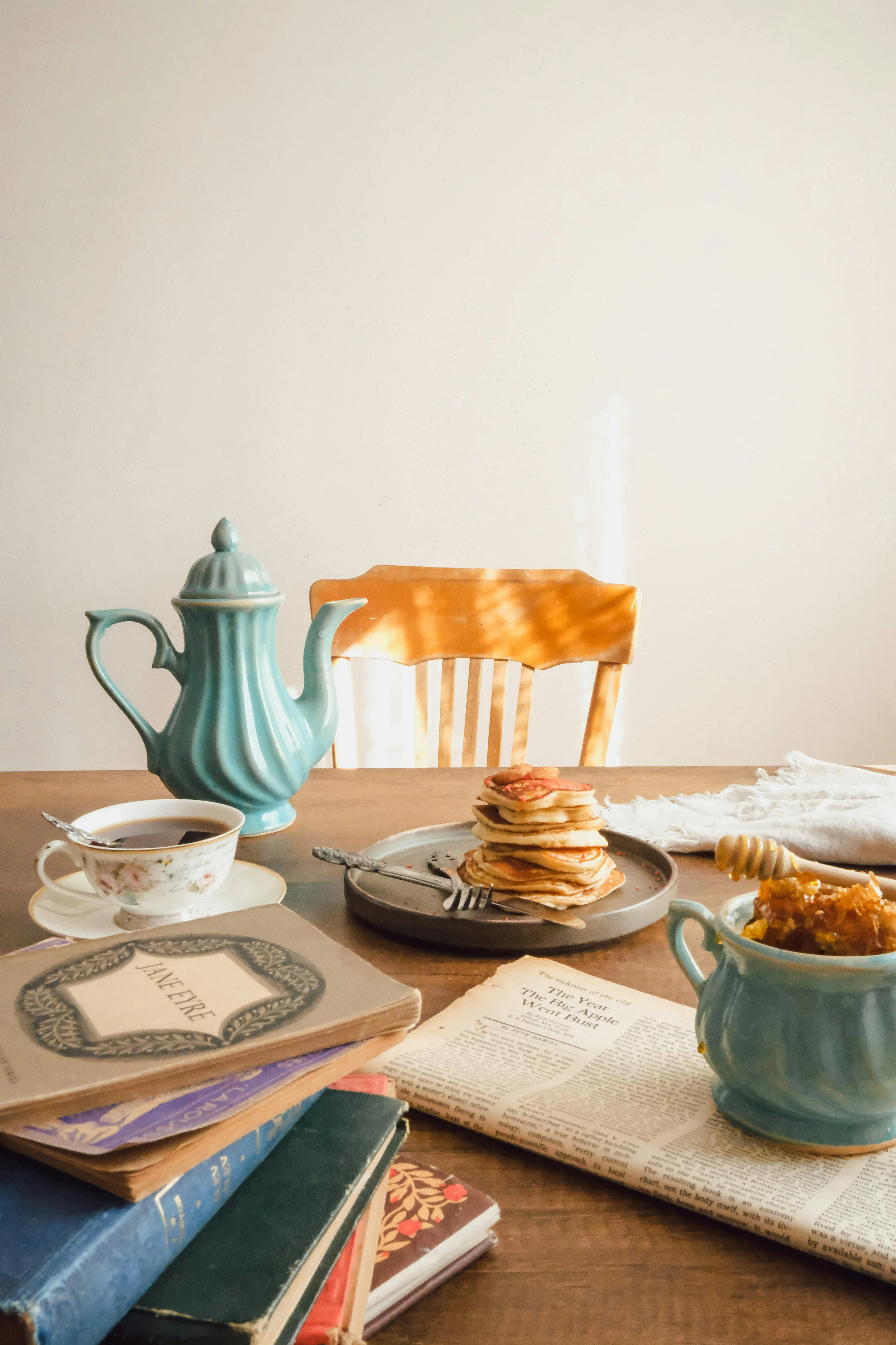 A warm, inviting breakfast scene featuring pancakes, coffee, and a vintage teapot on a wooden table.