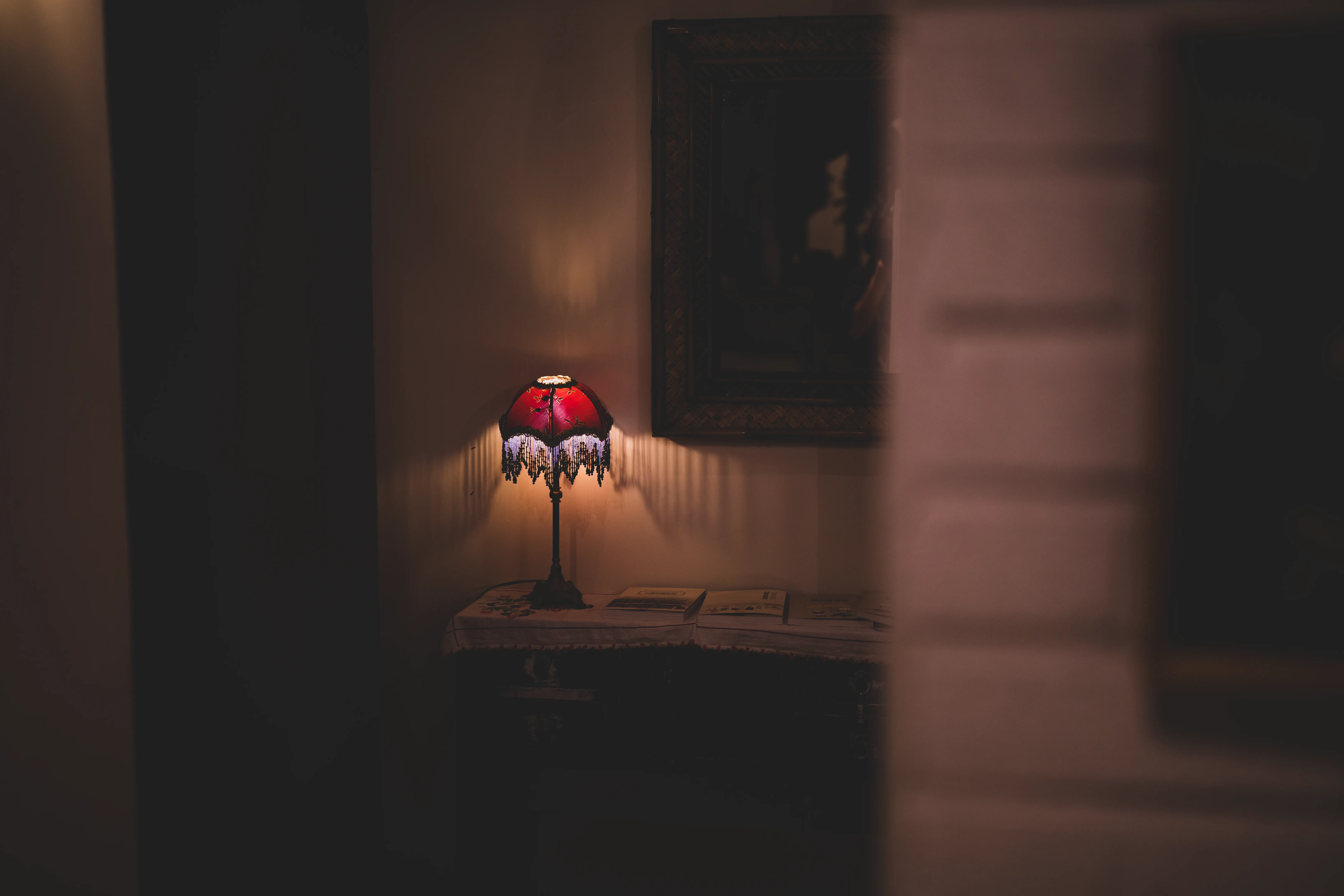 A warm, moody interior featuring a vintage lamp casting a soft glow on a table.