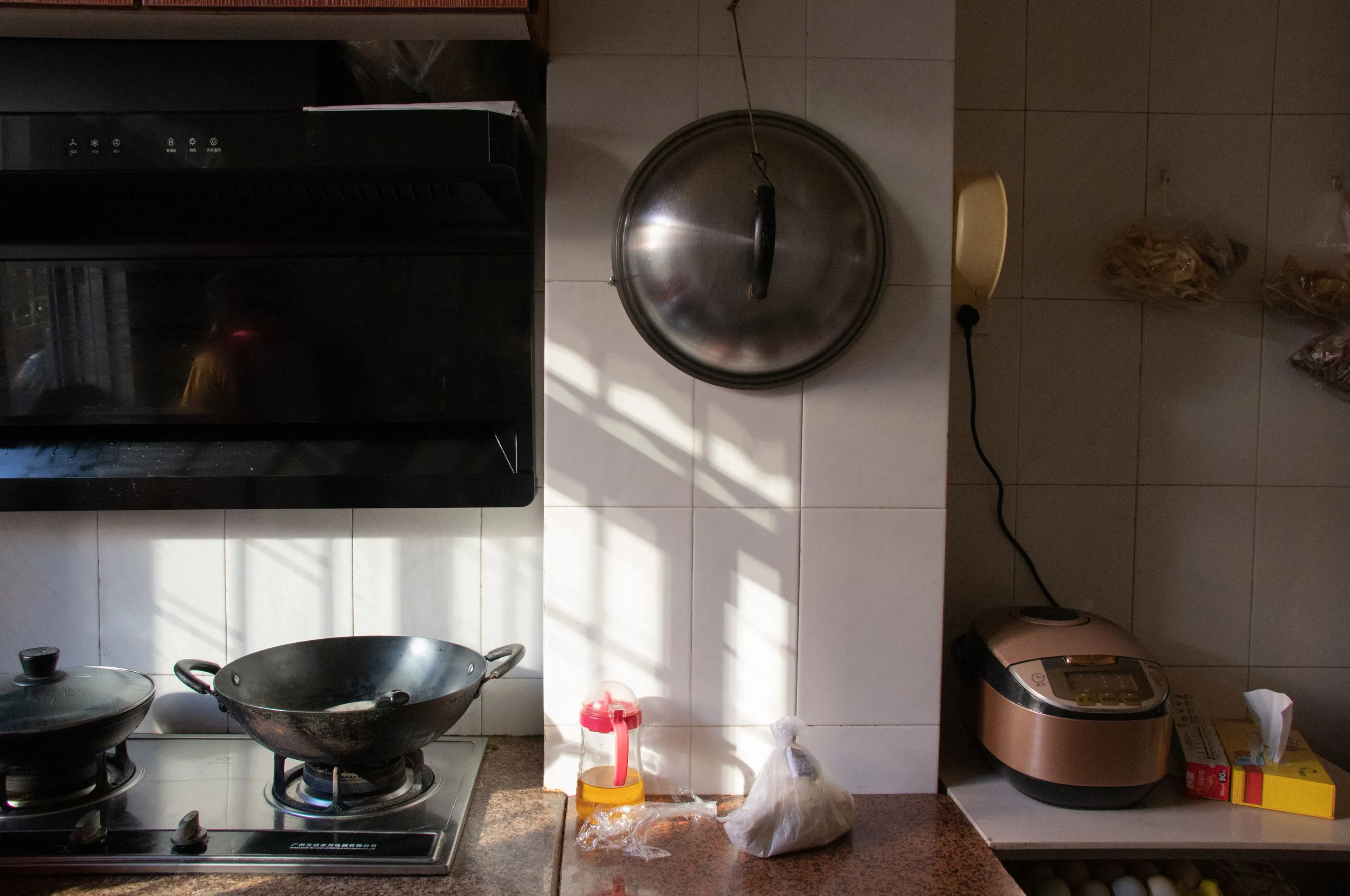 Warm, sunlit kitchen with cookware, stove, and appliances. Includes wok and rice cooker.