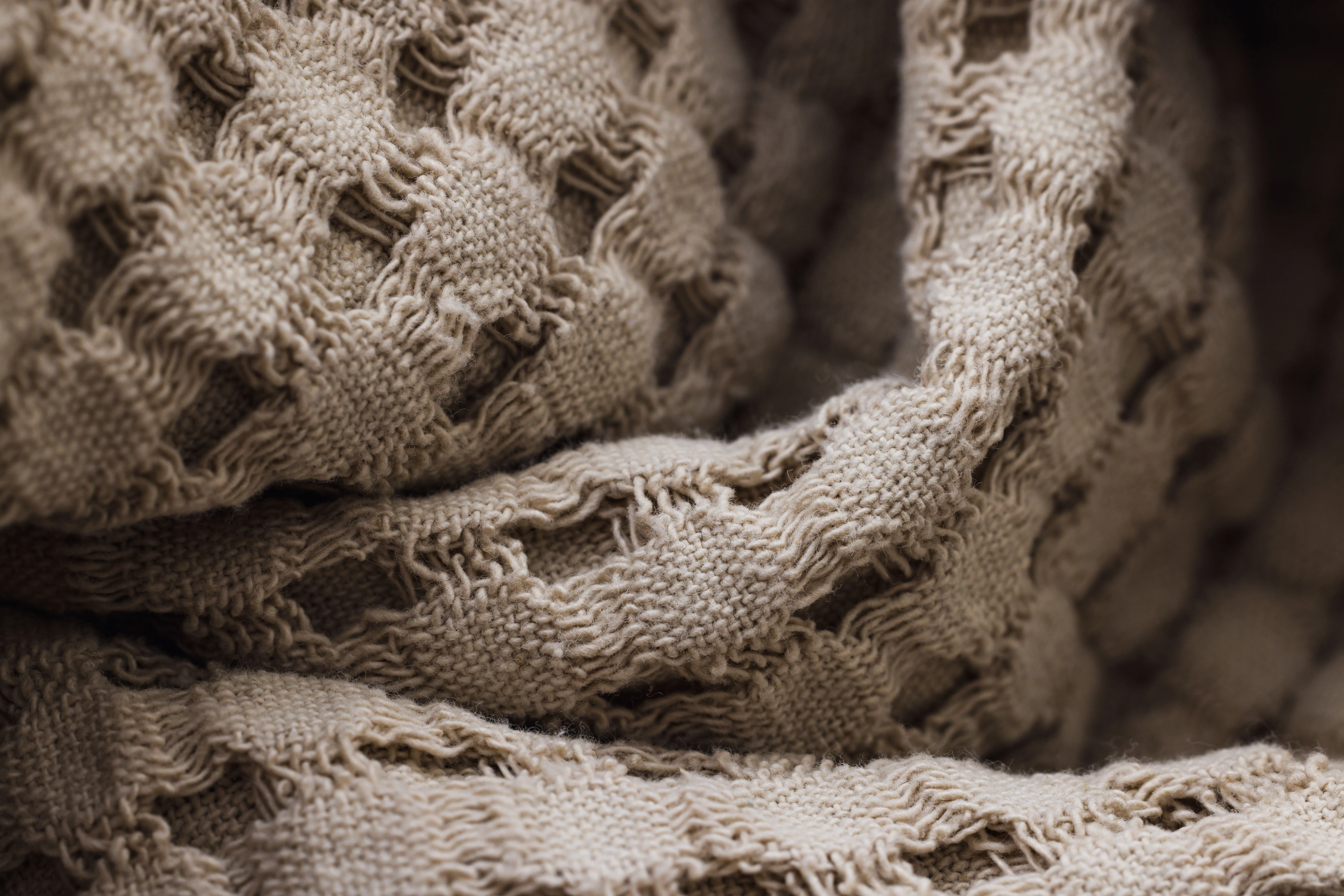 Detailed close-up of tan woven fabric texture showing intricate patterns and detailing.