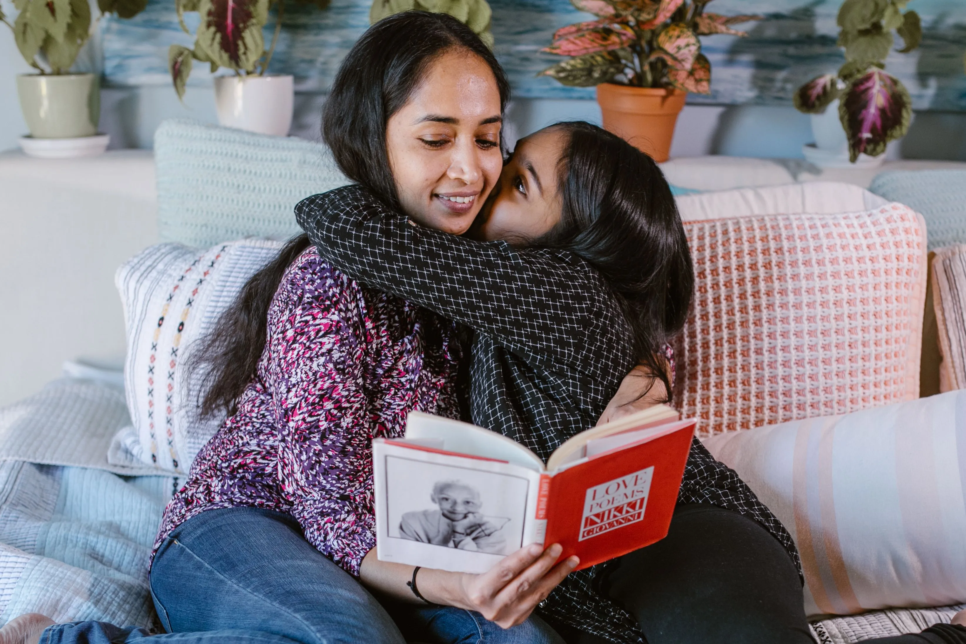 A loving mother and daughter share a tender moment reading together on a cozy bed.