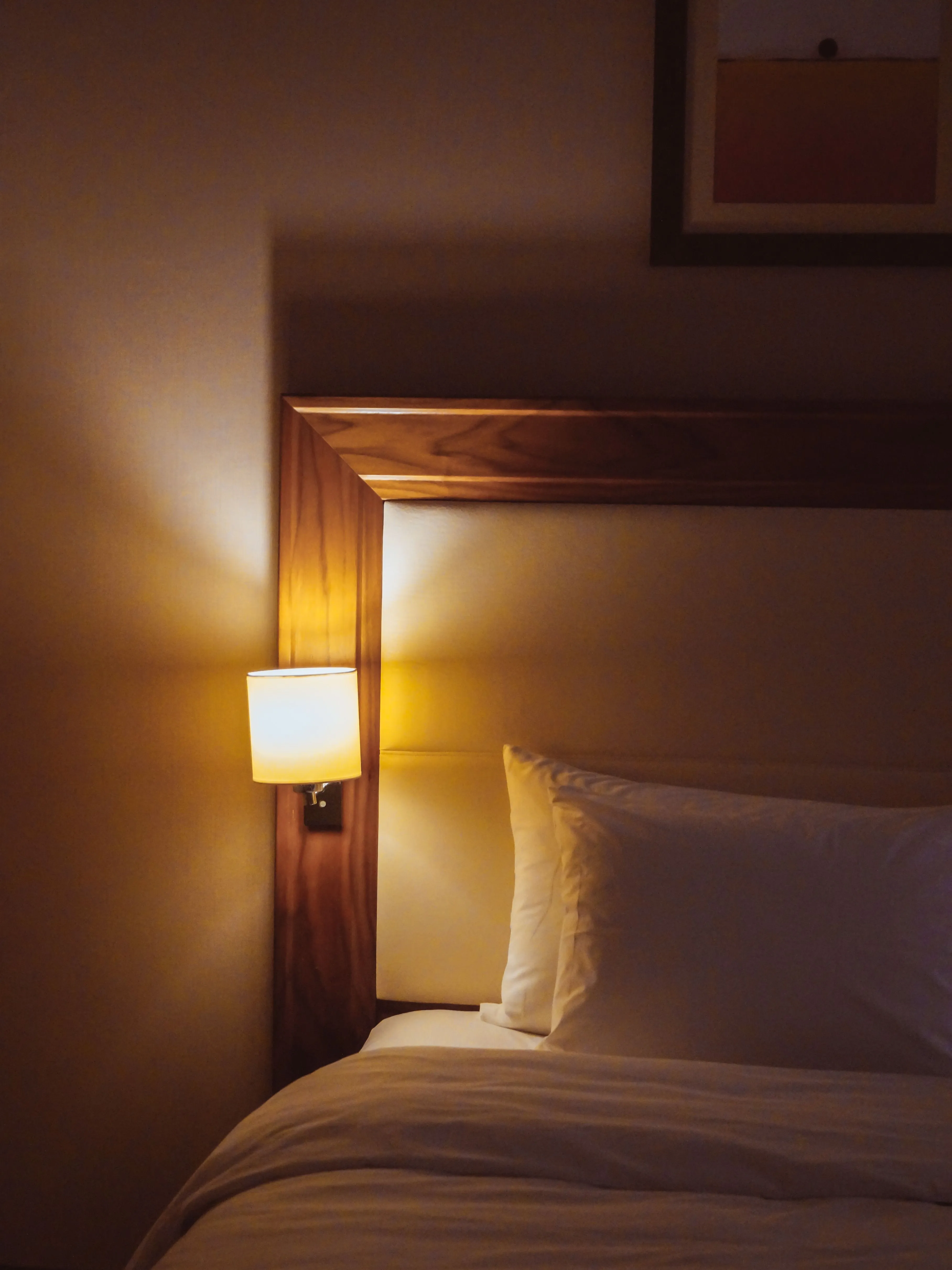 A warm and inviting minimalist bedroom featuring soft lighting, a comfortable bed, and a stylish headboard.
