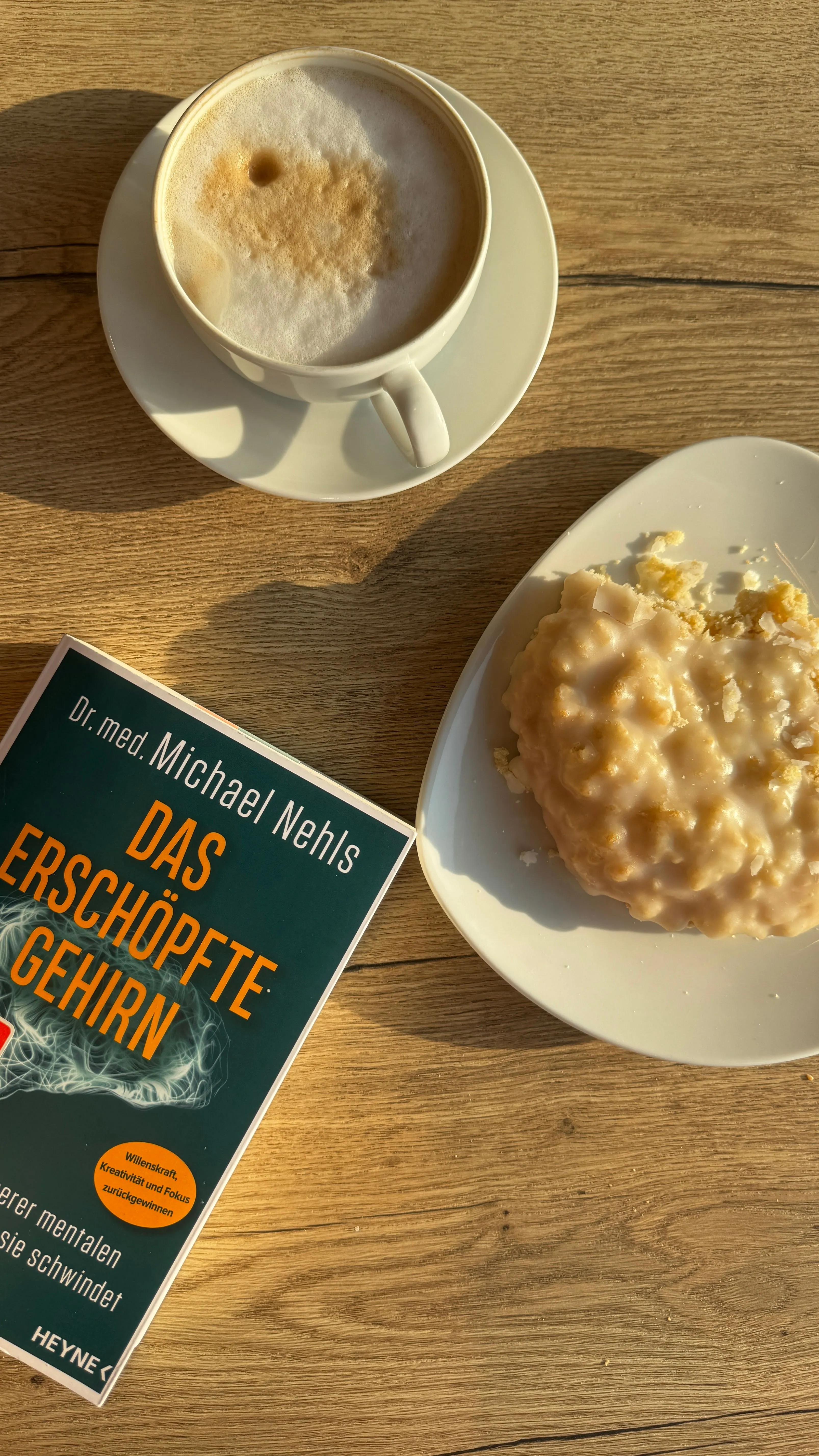 Cozy morning with cappuccino, pastry, and book in Berlin sunlight.